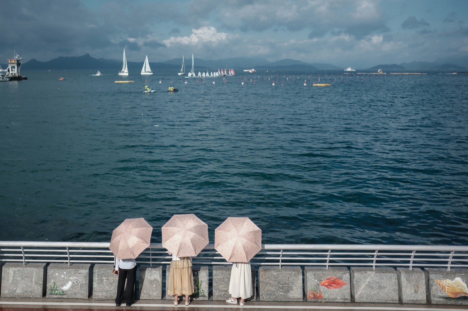 看 海-2023年6月20日，深圳南澳海邊，烈日下，游客打傘看海，遠(yuǎn)處是在為端午舉辦龍舟賽正在進(jìn)行訓(xùn)練的賽手們。-薛云麾.jpg
